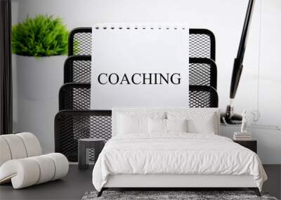 Business concept. The phrase, text,words COACHING is written on white paper in a black stand on a light background Wall mural