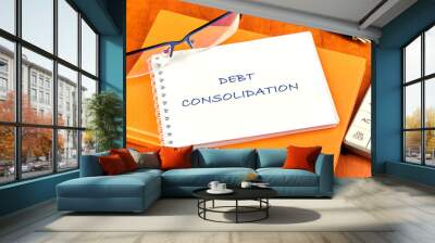 Debt consolidation. This is the process of obtaining a new loan to repay a number of existing debts. The text is written on a clean white notebook Wall mural