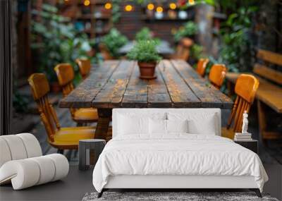 A wooden table with yellow chairs surrounding it, topped with a potted plant Wall mural