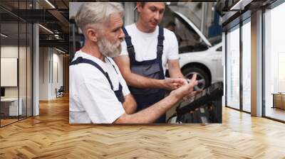 Vertical shot of two car service mechanics working together at the garage Wall mural