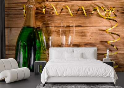 Bottle of champagne and two wineglasses decorated with golden ribbon on wooden table. Top view Wall mural