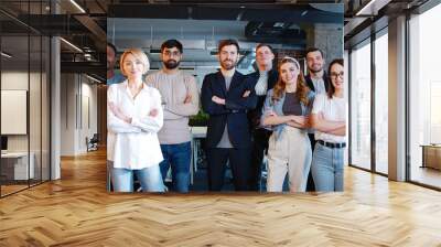 Portrait of multiethnic business team standing in office smiling to camera and crossing hands. Diverse coworkers. Young men and women, coworkers of IT startup. Business colleagues. Management strategy Wall mural