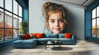 Portrait of a cute little girl in a blue shirt on a gray background Wall mural