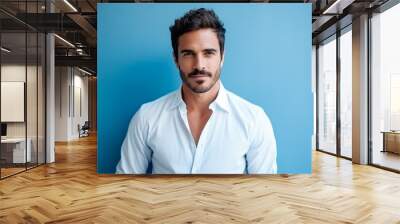 Portrait of a handsome young man in white shirt over blue background Wall mural