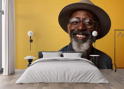 Portrait of a happy senior man in hat and glasses over yellow background Wall mural