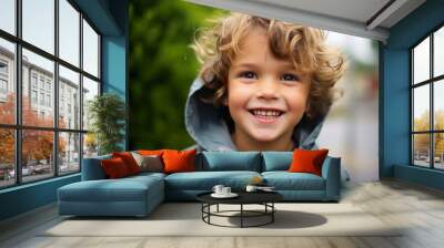 Portrait of a smiling little boy in a blue raincoat. Wall mural