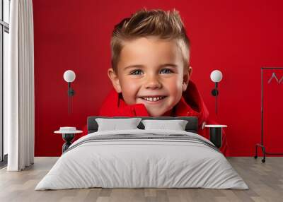 Portrait of a smiling little boy in a red jacket on a red background Wall mural