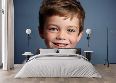 Portrait of a smiling little boy on a blue background. Studio shot. Wall mural