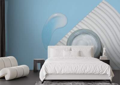 Face cream in frosted glass jar on white wavy podium and smear on light blue background, top view Wall mural