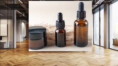 Side view composition with dark glass dropper bottles with essential oil and cream jar and dry reeds. home spa and skin care concept Wall mural