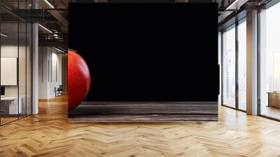 A solitary tomato rests on a weathered black wooden table providing a striking visual with ample copy space Wall mural