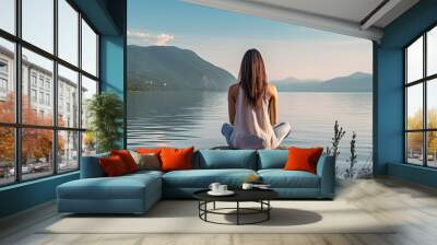 A woman is seen meditating on a hill overlooking the sea in a peaceful setting, with a view from behind, providing ample space for adding text to the image. Wall mural