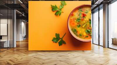 An overhead shot of vegetable soup in a bowl against a light orange backdrop with copy space image. Wall mural