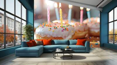 Donuts with icing and candles on a table with a bright, copy space image in the background. Wall mural