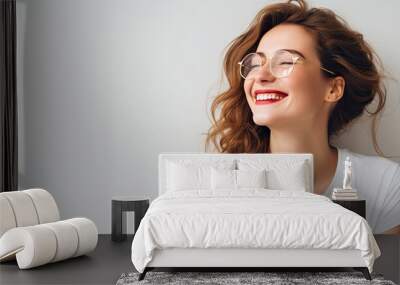 Joyful young woman in a white t shirt and glasses with a carefree expression happily relaxing at home in a horizontal studio copy space image Wall mural