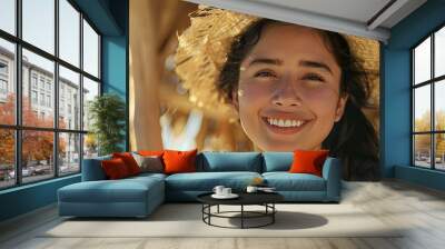 On a sandy beach a cheerful young Latina woman in casual summer attire beams with joy backed by a straw shelter providing ideal copy space image Wall mural