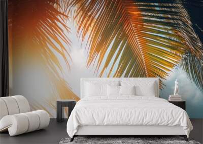 Palm tree branches photographed from below against a sunset sky with sunlight filtering through the leaves creating a beautiful travel themed copy space image Wall mural