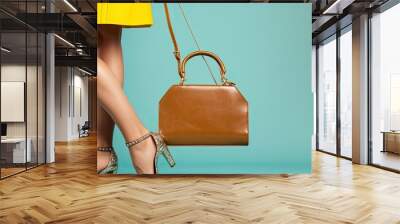 Picture of attractive woman s legs in summer shoes dressed in a stylish brown yellow outfit accessorized with a blue mint clutch on a white background with copy space image Wall mural