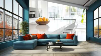 A modern kitchen island showcases a bowl of fresh fruit amidst neatly organized barstools, illuminated by abundant natural light pouring through large windows Wall mural