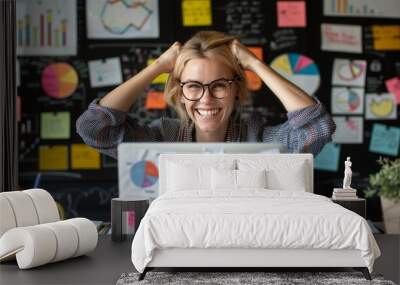 Excited young businesswoman celebrating success with arms up in front of laptop screen Wall mural