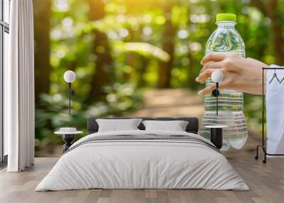 Hand holding water bottle with damp towel, demonstrating visible signs of perspiration Wall mural