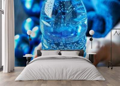 Hand holding water bottle with sweat dampened towel draped over it for hydration Wall mural