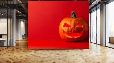 Smiling spooky halloween pumpkin with illuminated scary face on red background with copy-space Wall mural