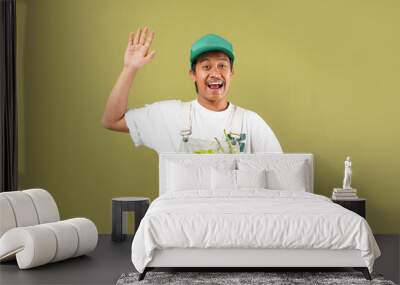 Farm Worker. Portrait Of Joyful Asian man Posing With Organic Vegetables In Wooden Box, Wearing Hat  Standing In Studio On Green Background. Successful Agriculture Business Wall mural