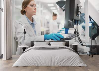 A team of laboratory technicians conduct a series of tests on a chemical analyzer in a biological laboratory. Two female scientists work in a modern equipped computer laboratory Wall mural