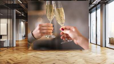 Female hands close up at christmas lights background hold champagne glasses Wall mural