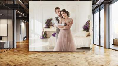 Happy tenderness couple in stylish interior. Well-dressed couple in love hugging in luxury hotel room Wall mural