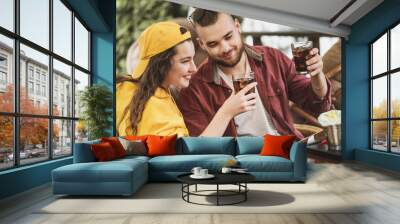 Young couple in love having fun spending leisure time together at restaurant, eating burgers and french fries, drinking cola  Wall mural