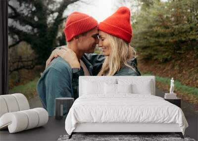 A couple of a man and a woman in red hats gently hug. Wall mural