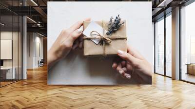 A gift box in a simple concise paper package with a card and a bouquet of lavender in hands with a holographic manicure. Thanksgiving and love concept, charity and natural materials. Zero waste. Wall mural