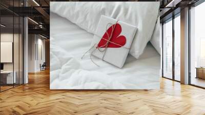 A gift box with a big paper heart lies in bed early in the morning. Content for honeymooners and lovers for Valentine's Day. Wall mural