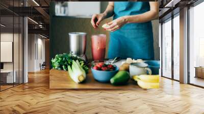 A woman puts the ingredients in a blender bowl to make a spring fruit and berry smoothie. Cooking at home in the kitchen, care and nutrition and health. Wall mural