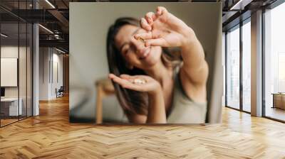 Happy smiling woman holding an omega pill in her hand. Wall mural