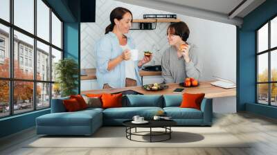 Relationship between a teenager and a parent. Mom and teenage daughter are having breakfast in the kitchen. Wall mural