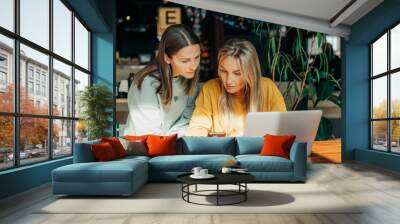 Two business women work behind the counter using electronic gadgets. Wall mural