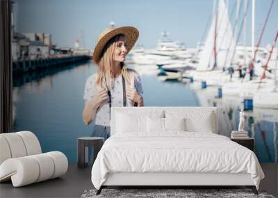 Young beautiful healthy woman walks in the harbor on the background of the yacht mooring. Wall mural