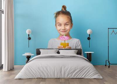 Cute little girl enjoying orange juice on blue isolated background. Wall mural