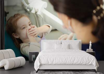 Kid afraid of procedure closes mouth with hands Wall mural