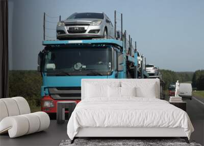 Loaded two level used car carrier trucks with car transporter semi trailers drive on suburban highway road at summer day. Front side view close up. Delivery autos logistics. Automobile transportation Wall mural