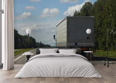 One European awning van semi truck back side closeup view drive on the suburban highway road at Sunny summer day on blue sky with white clouds background, cargo trucking transportation logistics Wall mural