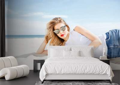 Attractive girl in sunglasses posing lying on the sea beach  Wall mural