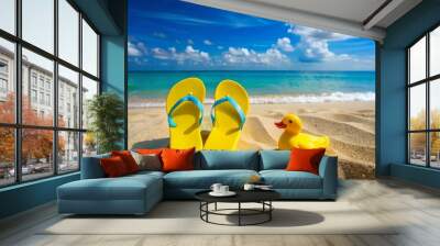 Beach flip-flops and yellow duck on the sand against blue sea and sky background. Summer vacation concept Wall mural