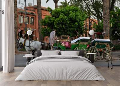 the famous colorful carriage and tourists in traditional Jamaa el Fna square (also Jemaa el-Fnaa, Medina , Djema el-Fna or Djemaa el-Fnaa) in Marrakesh, Morroco Wall mural