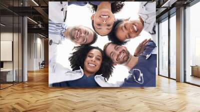 Happy people, portrait and doctors in huddle, teamwork or unity in healthcare mission together below. Low angle of excited group of medical professionals smile in team building, support or goals Wall mural