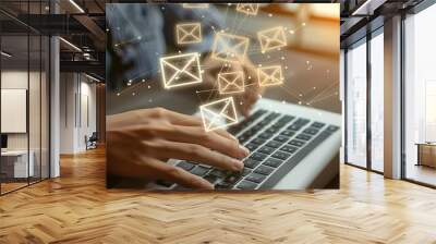 A person typing on a laptop with email icons hovering above the keyboard. Wall mural