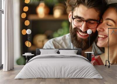 A man and woman are hugging and smiling while holding a red present. Scene is happy and loving Wall mural